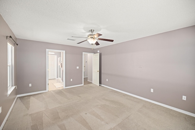 unfurnished bedroom with light carpet, a textured ceiling, visible vents, and baseboards