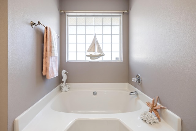 full bath featuring a bath and a textured wall