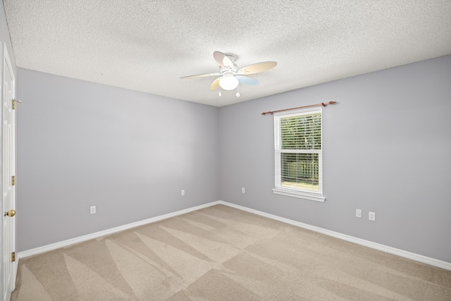 unfurnished room featuring light carpet, ceiling fan, a textured ceiling, and baseboards