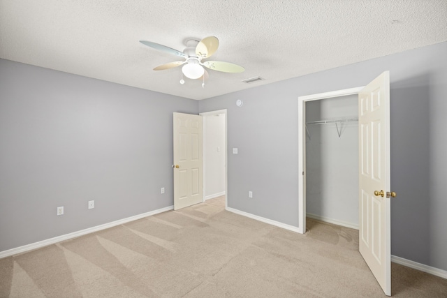 unfurnished bedroom with a textured ceiling, ceiling fan, light carpet, visible vents, and baseboards