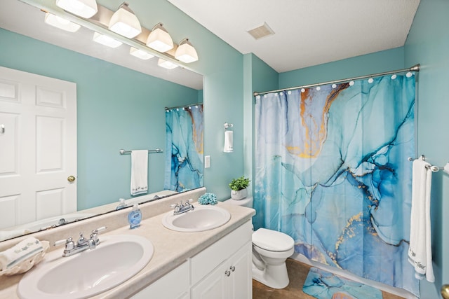 bathroom featuring toilet, tile patterned flooring, double vanity, and a sink