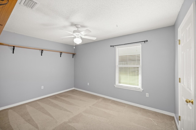 unfurnished room featuring ceiling fan, a textured ceiling, light carpet, visible vents, and baseboards