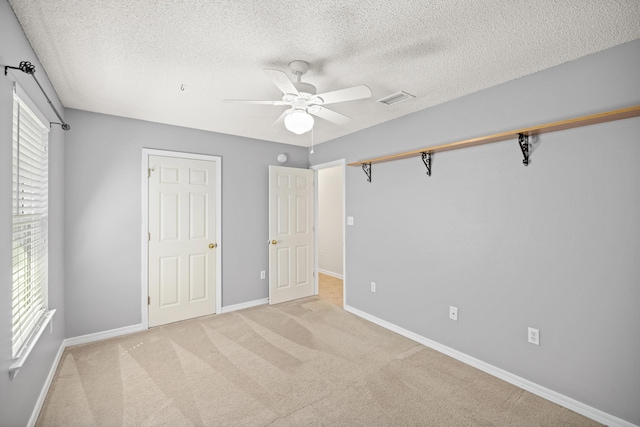 unfurnished bedroom with light carpet, baseboards, visible vents, a ceiling fan, and a textured ceiling