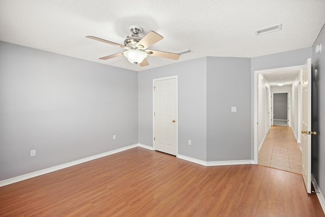 unfurnished bedroom with light wood-style floors, baseboards, visible vents, and a textured ceiling