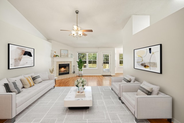 living room with a fireplace, light wood finished floors, lofted ceiling, ceiling fan, and baseboards