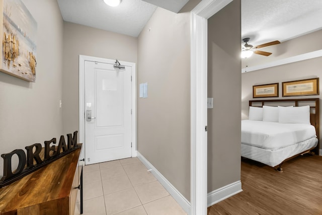 entrance foyer featuring light tile patterned flooring, ceiling fan, a textured ceiling, and baseboards