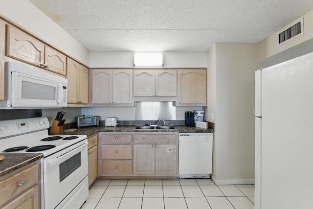 kitchen featuring dark countertops, visible vents, white appliances, and a sink