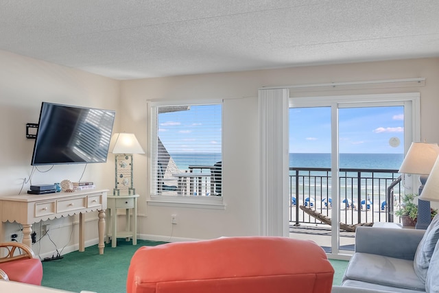 living room with baseboards, a water view, a textured ceiling, and carpet flooring