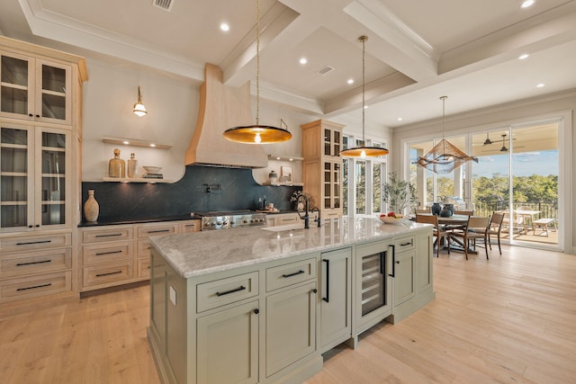 kitchen with light wood finished floors, range, wine cooler, beamed ceiling, and a sink