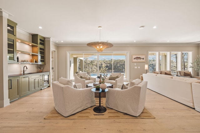 living room with beverage cooler, wet bar, crown molding, light wood-style floors, and recessed lighting