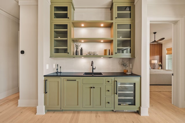 bar with light wood-style floors, wine cooler, wet bar, and a sink