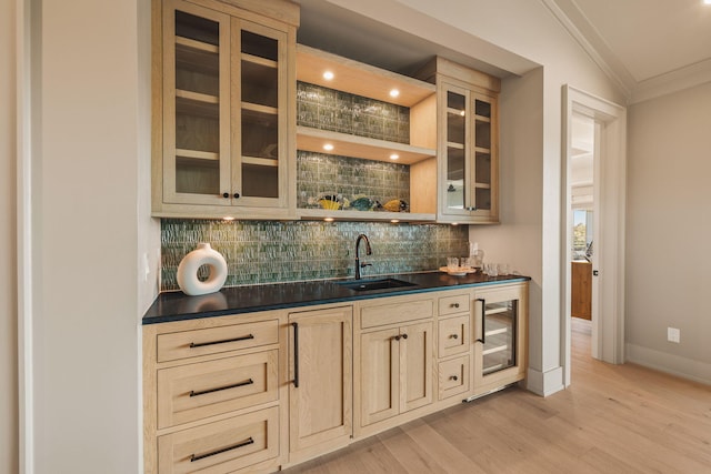 bar featuring wine cooler, a sink, ornamental molding, light wood-type flooring, and decorative backsplash