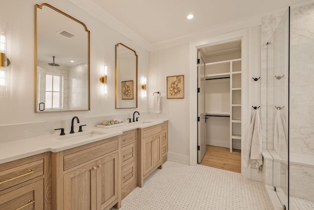 full bathroom with a shower with door, a spacious closet, ornamental molding, and a sink