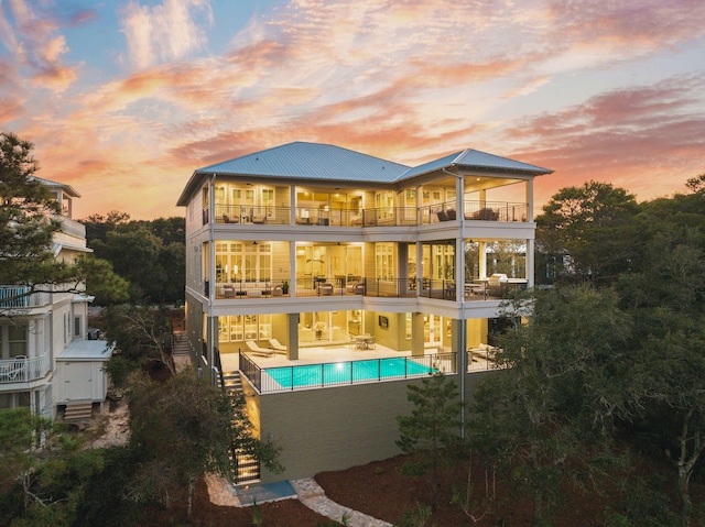 back of house featuring a balcony, an outdoor pool, and a patio