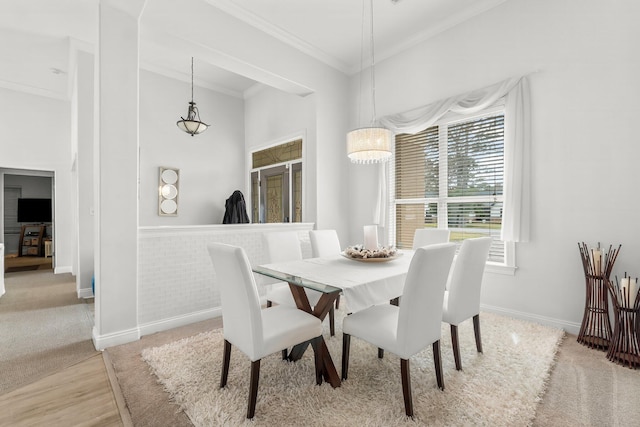 dining space featuring light wood-style floors, crown molding, and baseboards