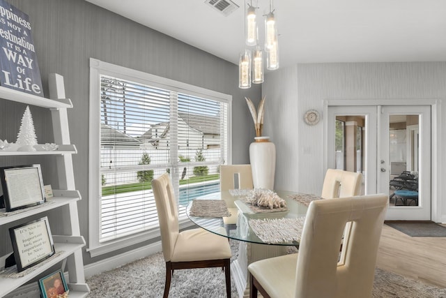 dining area featuring light wood-type flooring, wallpapered walls, visible vents, and french doors