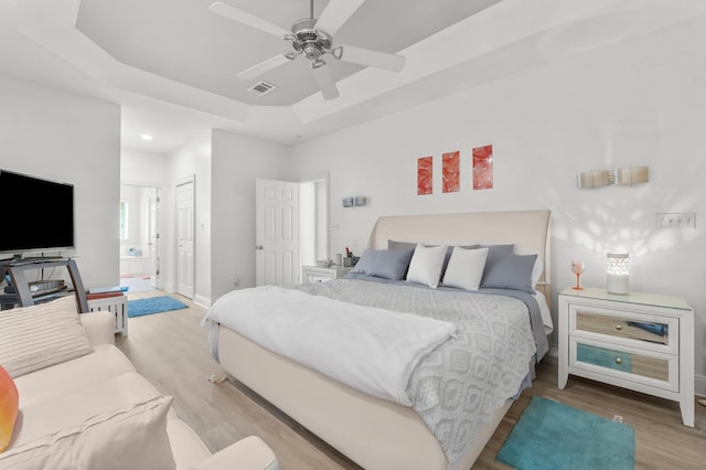 bedroom featuring light wood-style flooring, visible vents, baseboards, a closet, and a tray ceiling