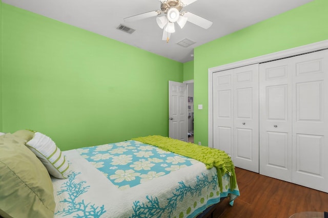 bedroom featuring ceiling fan, a closet, visible vents, and dark wood-style flooring