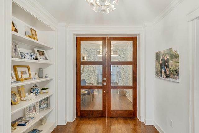 entryway with built in shelves, a notable chandelier, wood finished floors, baseboards, and french doors