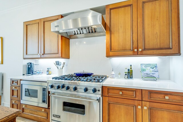 kitchen featuring stainless steel appliances, brown cabinets, and wall chimney exhaust hood