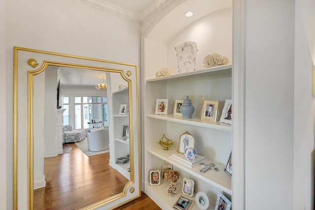 interior details with built in shelves, crown molding, and wood finished floors