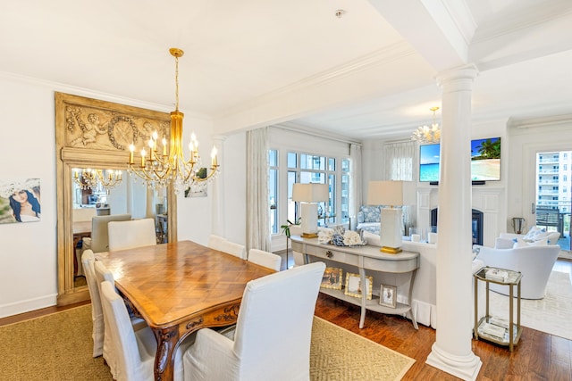 dining room featuring a wealth of natural light, wood finished floors, decorative columns, and an inviting chandelier