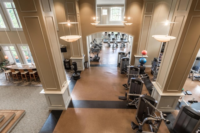 exercise room featuring a high ceiling and ornate columns