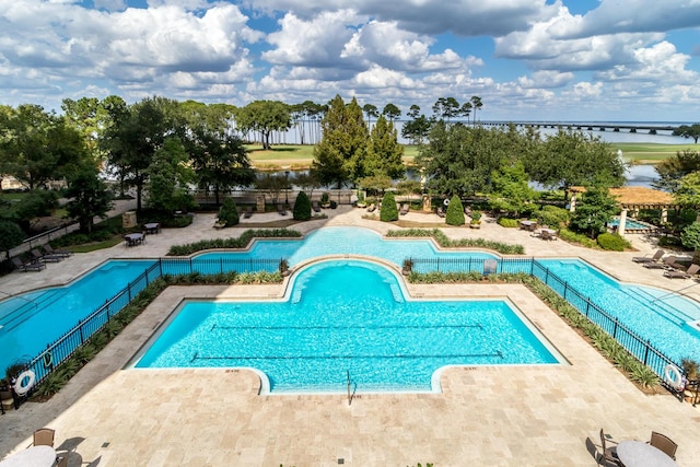 community pool featuring a patio, a water view, and fence