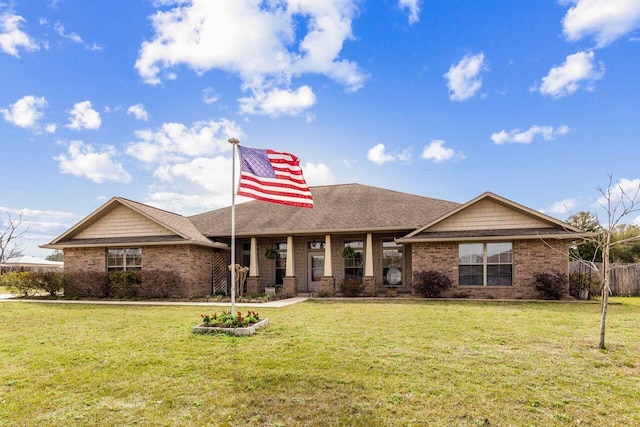 view of front of house with brick siding, a front lawn, and roof with shingles