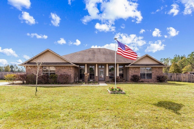 view of front of home featuring brick siding, fence, and a front lawn