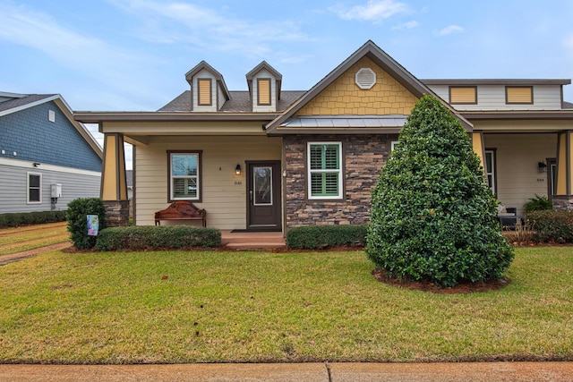 craftsman-style home with covered porch, a standing seam roof, metal roof, stone siding, and a front lawn