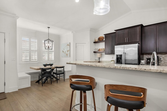846 Cannon Ln, Destin, FL 32541 - kitchen with dark brown cabinetry, stainless steel fridge, light stone counters, hanging light fixtures, and light wood-style floors
