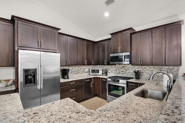 846 Cannon Ln, Destin, FL 32541 - kitchen with visible vents, appliances with stainless steel finishes, light stone countertops, vaulted ceiling, and a sink