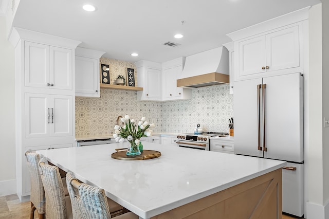 kitchen with premium appliances, premium range hood, visible vents, white cabinetry, and open shelves