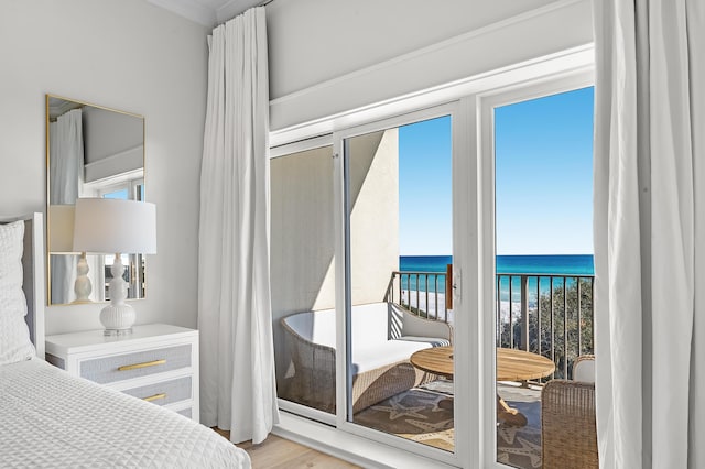 bedroom featuring a water view, access to exterior, and light wood-style flooring