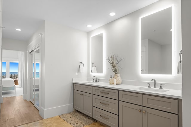 full bath with a sink, double vanity, connected bathroom, and recessed lighting