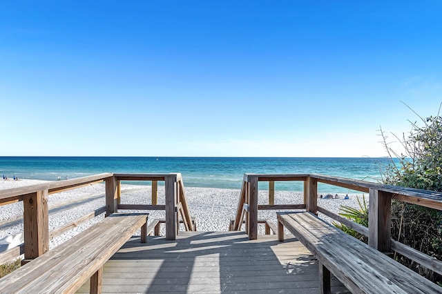 view of property's community featuring a deck with water view and a beach view