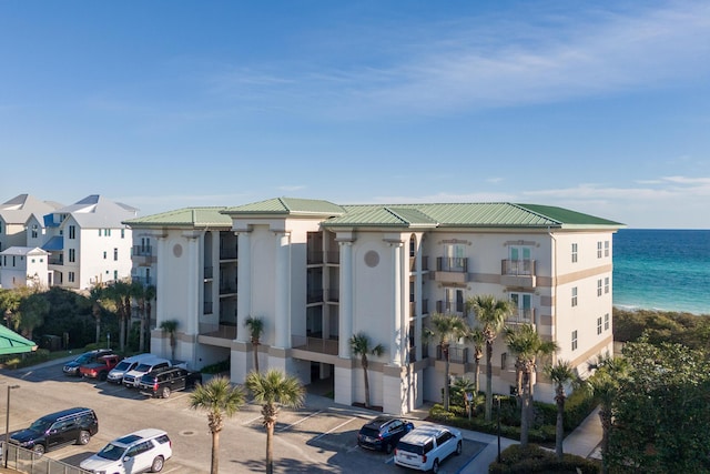 view of building exterior with uncovered parking and a water view