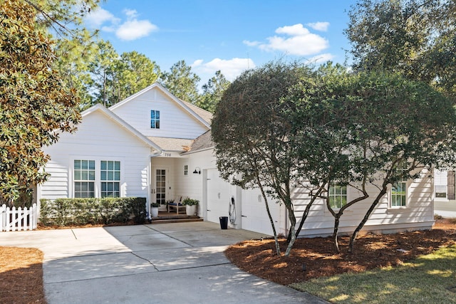 view of front of house with driveway, an attached garage, fence, and roof with shingles