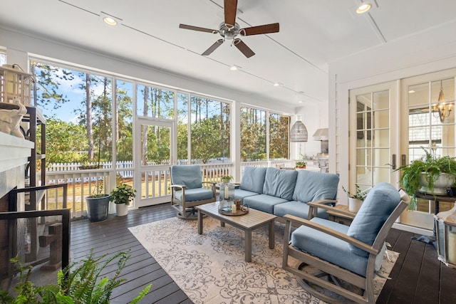 sunroom / solarium with a fireplace, a ceiling fan, and a wealth of natural light