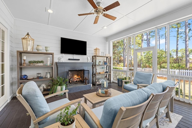 sunroom / solarium with ceiling fan and a lit fireplace