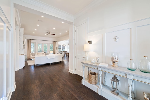 corridor with crown molding, recessed lighting, wood finished floors, and a decorative wall