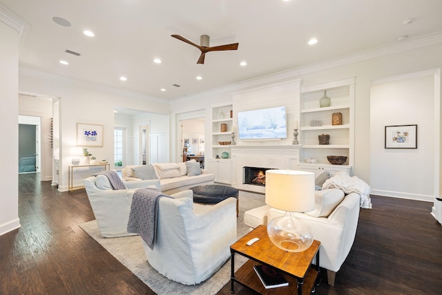 living area with dark wood-style floors, a premium fireplace, baseboards, and crown molding