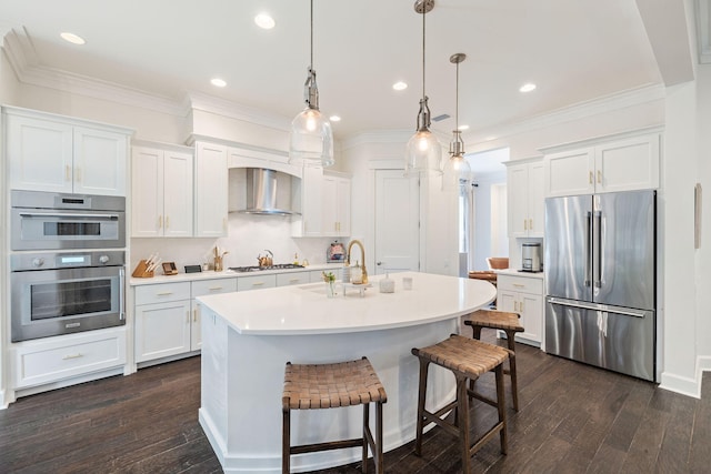 kitchen featuring appliances with stainless steel finishes, white cabinets, light countertops, and wall chimney range hood