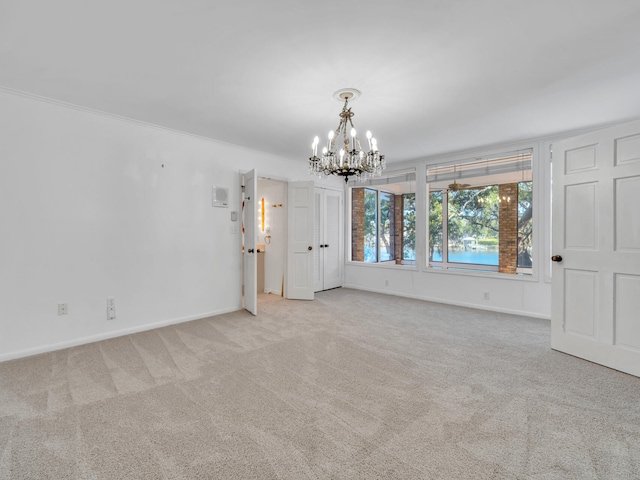 spare room with baseboards, carpet, a chandelier, and crown molding