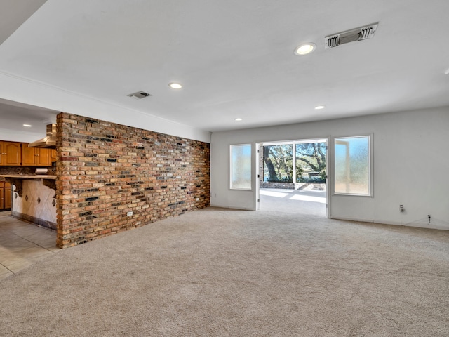 unfurnished living room featuring visible vents, light colored carpet, and brick wall