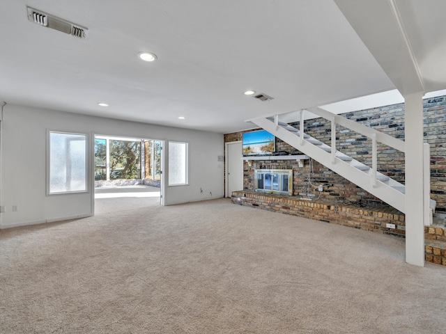 unfurnished living room with visible vents, recessed lighting, a brick fireplace, and carpet