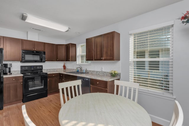 79 N 6th St, Santa Rosa Beach, FL 32459 - kitchen with light countertops, visible vents, light wood-style flooring, a sink, and black appliances