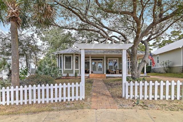 view of front of house featuring a fenced front yard, metal roof, covered porch, a standing seam roof, and french doors