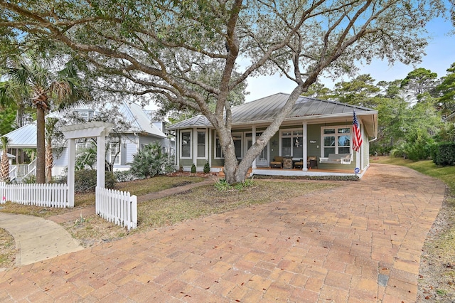 bungalow-style house featuring covered porch, metal roof, a pergola, and fence